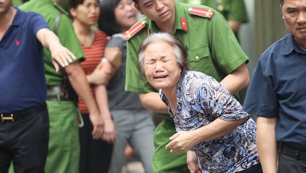 Người thân khóc nghẹn khi lực lượng chức năng đưa thi thể bà cụ ra ngoài. - Sputnik Việt Nam