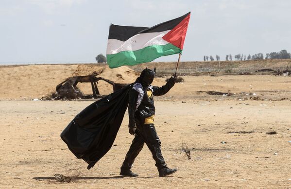 Một người biểu tình Palestine ăn mặc như Batman với quốc kỳ trong tay gần biên giới giữa Israel và Gaza - Sputnik Việt Nam