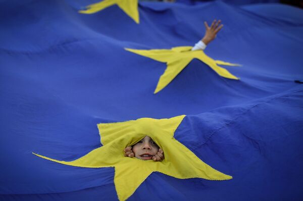 Cậu bé nhìn qua lá cờ EU trong cuộc biểu tình ở Bucharest - Sputnik Việt Nam