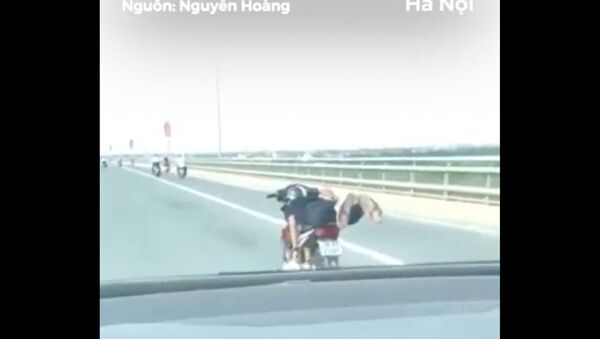 Thanh niên nằm trên xe máy chạy trên cầu Nhật Tân - Sputnik Việt Nam