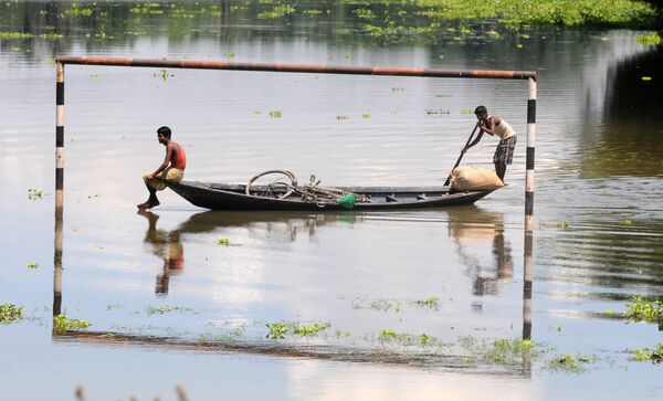 Những người dân địa phương đang đi trên thuyền qua khung thành bóng đá bị ngập dưới nước ở làng Mekata, Ấn Độ - Sputnik Việt Nam