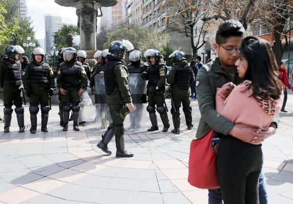 Cặp đôi đứng cạnh các cảnh sát đang chuẩn bị hành động trong cuộc biểu tình của các sinh viên UPEA ở La Paz, Bolivia - Sputnik Việt Nam