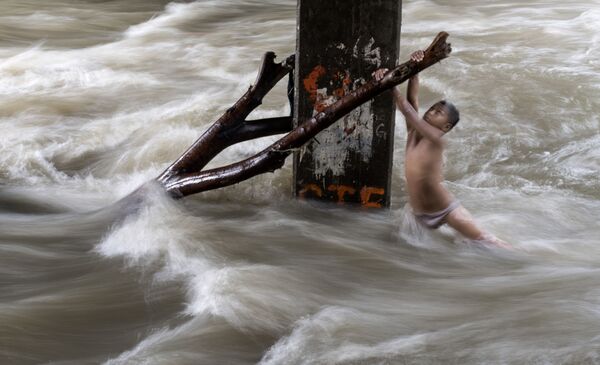 Trẻ em đang chơi dưới gầm cầu trên con song bị tràn nước do mưa lớn ở Manila, Philippines - Sputnik Việt Nam