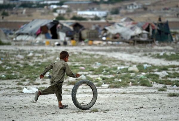 Cậu bé người Afghanistan chơi với lốp xe trong một khu trại của dân du mục, ngoại ô thủ đô Kabul. - Sputnik Việt Nam