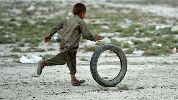 Cậu bé người Afghanistan chơi với lốp xe trong một khu trại của dân du mục, ngoại ô thủ đô Kabul. - Sputnik Việt Nam