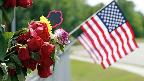 An American flag hangs next to bouquets of flowers on a barbed wire fence Sunday, May 10, 2015, at a makeshift memorial near the site where two Hattiesburg, Miss., police officers were shot to death during a Saturday evening traffic stop - Sputnik Việt Nam