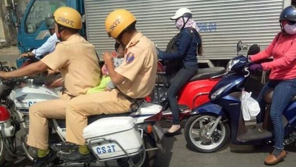 Hình ảnh hai anh CSGT thuộc phòng CSGT công an TPHCM bế cháu bé trên xe đặc chủng đưa đi bệnh viện. - Sputnik Việt Nam
