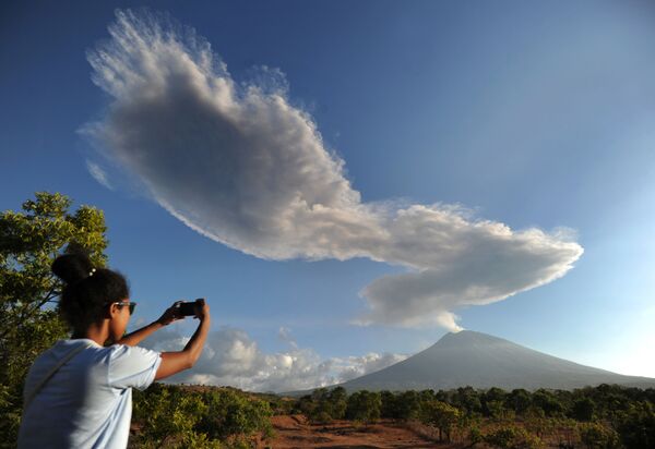 Một phụ nữ đang chụp ảnh núi lửa Agung đang bốc khói trên đảo Bali - Sputnik Việt Nam
