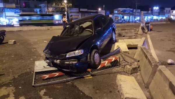 Hiện trường vụ tai nạn chiếc ô tô biển xanh tông sập rào chắn công trình. - Sputnik Việt Nam