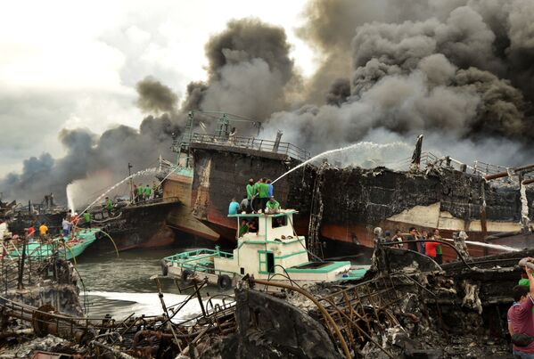 Công nhân và nhân viên cứu hỏa cố gắng dập đám cháy trên thuyền đánh cá ở Cảng Benoa, Denpasar, Indonesia - Sputnik Việt Nam