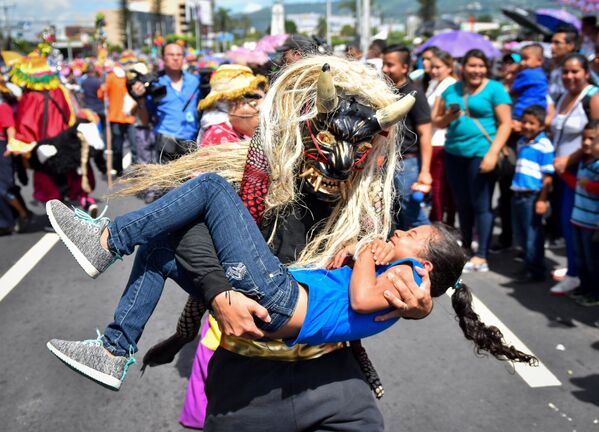 Một người trong mặt nạ của sinh vật thần thoại ôm cô gái trong vòng tay tại cuộc diễu hành ở San Salvador - Sputnik Việt Nam