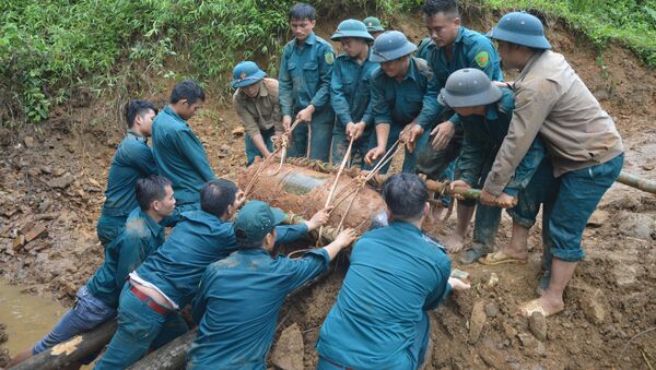 Chiến sỹ lực lượng vũ trang đưa bom xuống hố để hủy nổ. - Sputnik Việt Nam