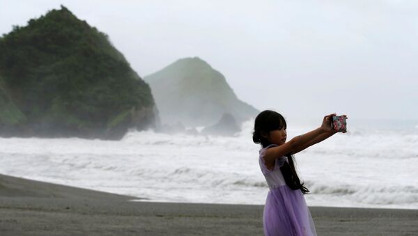 Cô gái đang chụp ảnh selfie trong khi xảy ra cơn bão Nepartak ở Đài Loan - Sputnik Việt Nam