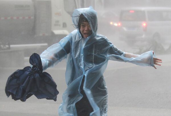 Một người phụ nữ trong trận mưa do một cơn bão Manghut gây ra tại Trung Quốc - Sputnik Việt Nam