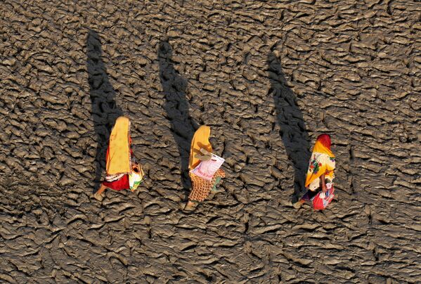 Những người phụ nữ đi trên bờ lầy bùn của dòng sông Hằng (Ấn Độ) sau nghi lễ tắm thanh tẩy - Sputnik Việt Nam