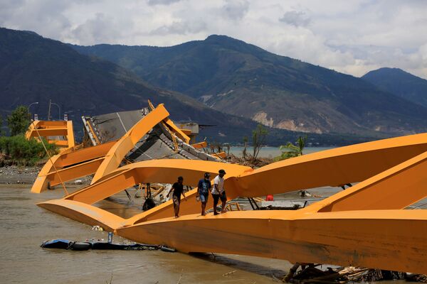Người qua sông theo cây cầu gẫy do trận động đất tại Palu trên đảo Sulawesi thuộc Indonesia - Sputnik Việt Nam