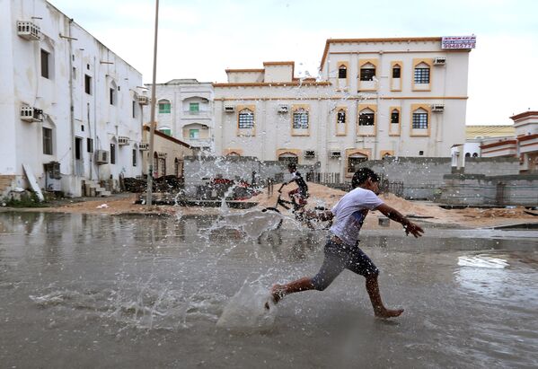 Trẻ em đang chơi trên đường phố bị ngập sau cơn bão Luban ở thành phố Salalah của Oman - Sputnik Việt Nam
