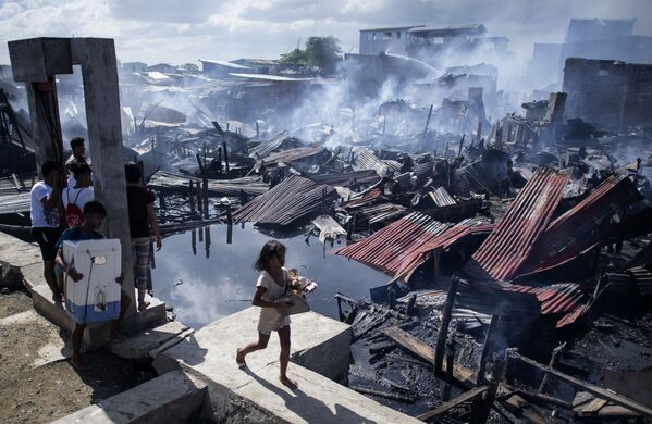Cô gái đi qua những ngôi nhà bị phá hủy sau một đám cháy khu ổ chuột ở Navotas, Philippines - Sputnik Việt Nam