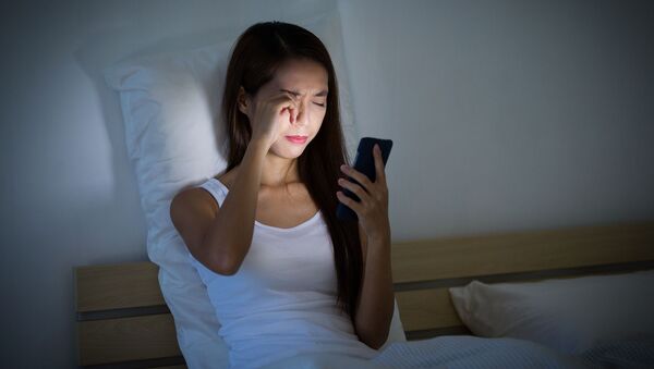 Cô gái nhìn vào điện thoại trên giường - Sputnik Việt Nam