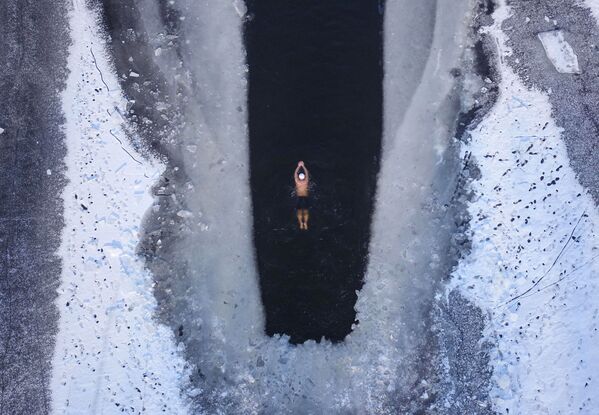 Một người đàn ông bơi trong hồ nước đóng băng một phần ở Thẩm Dương, tỉnh Liêu Ninh - Sputnik Việt Nam
