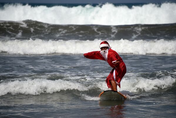 Người đàn ông mặc trang phục ông già Noel khi lướt sóng ở Bali - Sputnik Việt Nam