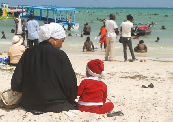 Cậu bé hóa trang thành ông già Noel bên cạnh mẹ trên bãi biển ở Kenya - Sputnik Việt Nam