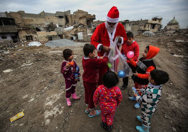 Một người đàn ông hóa trang thành ông già Noel phân phát quà cho trẻ em trên đường phố ở Mosul, Iraq - Sputnik Việt Nam