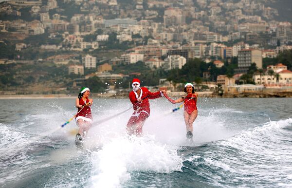 Các thanh niên lướt ván trong trang phục Santa Claus ở  vịnh Jounieh, Lebanon - Sputnik Việt Nam