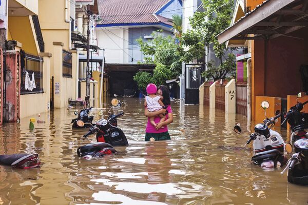 Người phụ nữ bế con trên con đường ngập nước ở thành phố Makassar, Indonesia - Sputnik Việt Nam