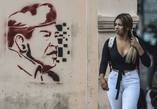 Người phụ nữ Caracas đi ngang ảnh cựu tổng thống Venezuela Hugo Chávez. - Sputnik Việt Nam