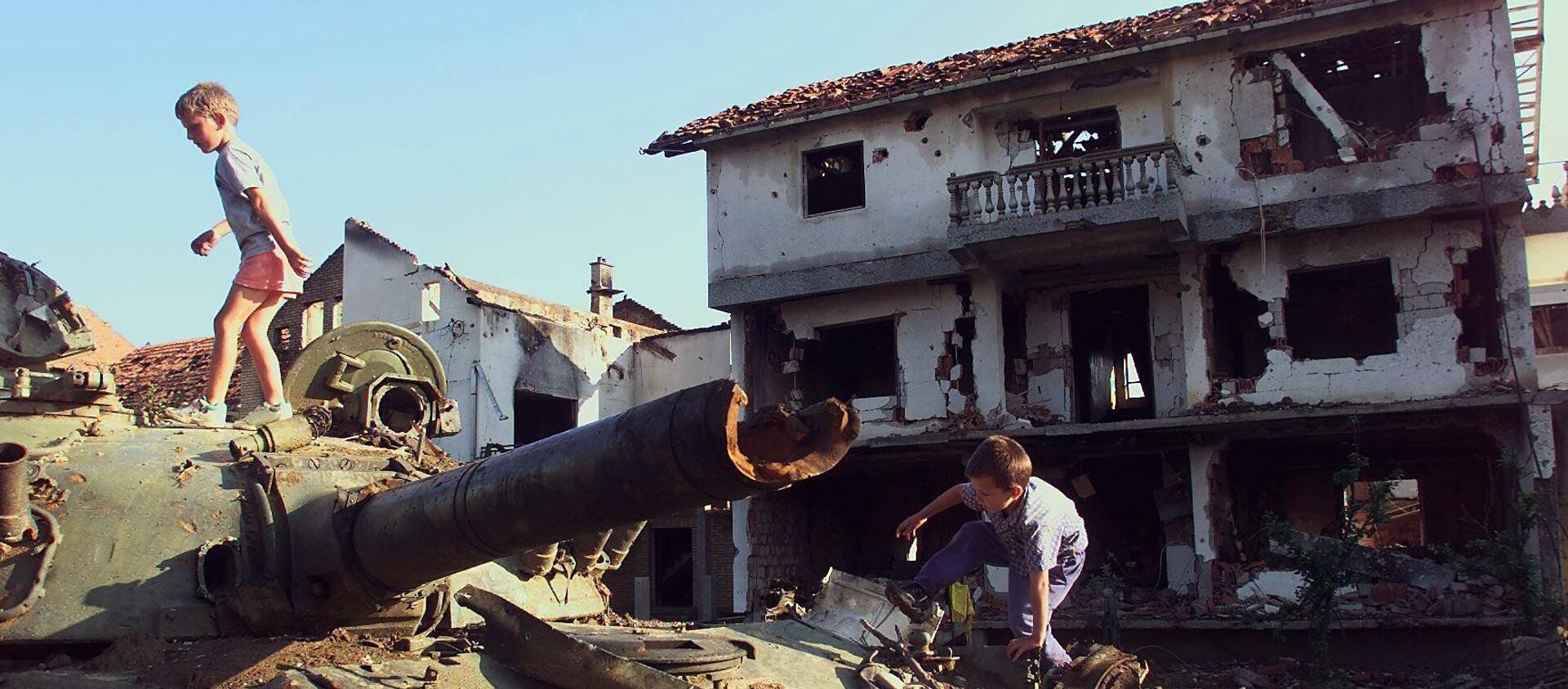 Trẻ em chơi trên chiếc xe tăng Serbia bị phá hủy trong vụ bắn phá của NATO tại thành phố Klina của Nam Tư, 1999 - Sputnik Việt Nam, 1920, 02.04.2019