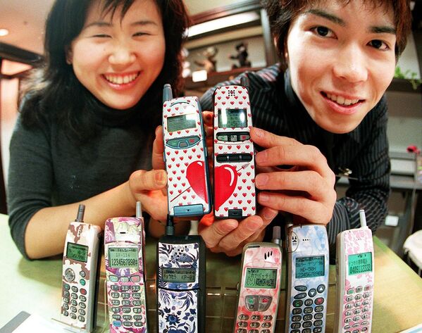 Cặp vợ chồng trẻ Nhật Bản khoe điện thoại di động dán mác hàng hiệu tại cửa hàng bách hóa Toki - Sputnik Việt Nam