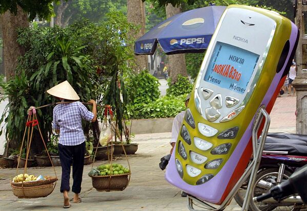 Người bán trái cây đi ngang qua cửa hàng điện thoại di động ở Hà Nội, Việt Nam. 2002 - Sputnik Việt Nam