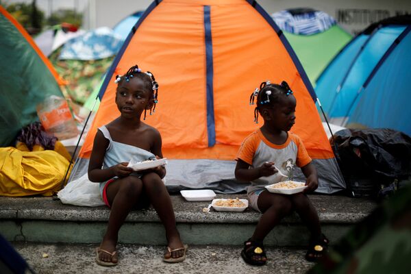 Hai cô bé Congo ngồi ăn bên lều trong trại ngẫu hứng gần Viện Di cư Quốc gia (INM) ở Tapachula, Mexico - Sputnik Việt Nam