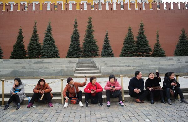 Nhóm du khách chụp ảnh kỷ niệm trên Quảng trường Đỏ bên tường thành Điện Kremlin Matxcơva  - Sputnik Việt Nam