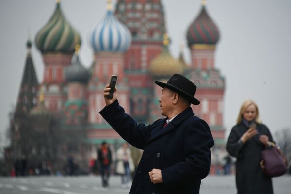 Một  vị du khách chụp ảnh trên Quảng trường Đỏ ở Matxcơva , trên nền Nhà thờ Thánh Vasily Blazhennyi  - Sputnik Việt Nam