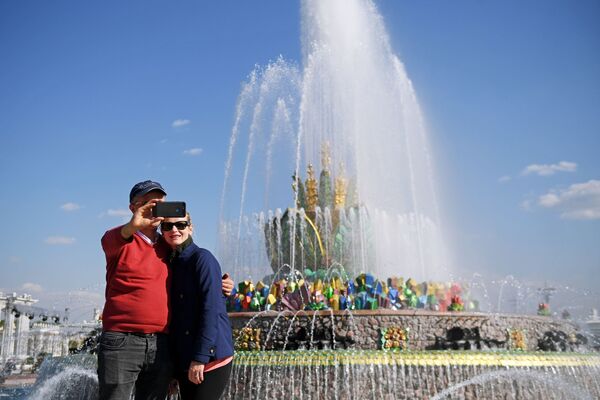 Các vị khách tham quan chụp ảnh bên Đài phun nước “Bông hoa đá” tại Triển lãm Thành tựu Kinh tế Quốc dân (VDNKh) ở Matxcơva  - Sputnik Việt Nam