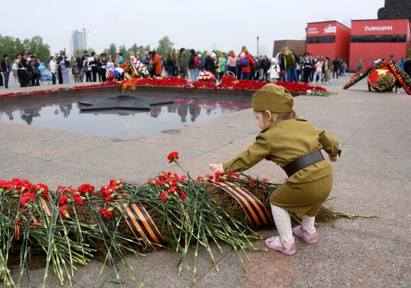 Bé gái đặt hoa ở Ngọn lửa Vĩnh cửu trên đồi Poklonnaya tại Matxcơva trong lễ hội Ngày Chiến thắng - Sputnik Việt Nam