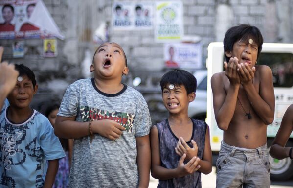Các cậu bé trong một cuộc thi chuyển đồng xu từ trán xuống đến miệng tại lễ hội hàng năm vinh danh Thánh Rita Kashiyskaya ở Manila - Sputnik Việt Nam