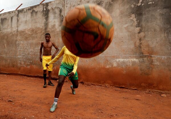 Gael Dule Asheri, 17 tuổi, thành viên của nhóm bận động nữ đầu tiên được các huấn luyện viên chuyên nghiệp từ Học viện Rails Foot ở Cameroon đào tạo, chơi bóng đá với bạn bè gần nhà ở Yaounde - Sputnik Việt Nam