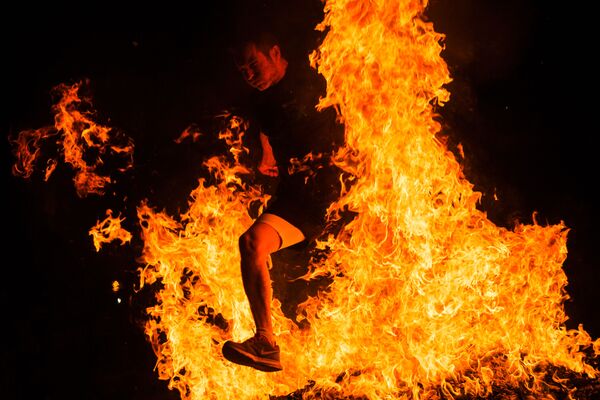 Người đàn ông nhảy qua đống lửa trong lễ kỷ niệm Đêm Thánh Juan ở Tây Ban Nha - Sputnik Việt Nam