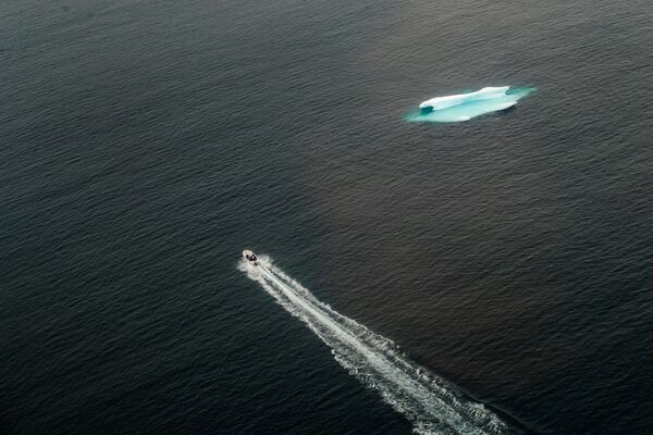 Một chiếc thuyền đi ngang qua tảng băng trôi trong đại dương gần Tasiilaq, Greenland - Sputnik Việt Nam