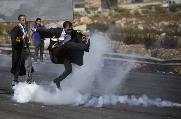 Một luật sư Palestine đá bình xịt hơi cay về phía các binh sĩ Israel trong cuộc biểu tình tại thành phố Ramallah, Palestine. - Sputnik Việt Nam