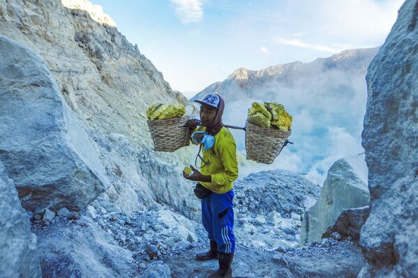  Thợ mỏ khuân vác túi lưu huỳnh từ mỏ đá trên núi lửa Kawah Ijen đang hoạt động ở Indonesia - Sputnik Việt Nam