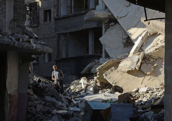 Một người dân địa phương trên đường phố giữa những tòa nhà bị phá hủy trong khu vực Dahane ở Damascus - Sputnik Việt Nam