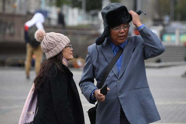 Khách du lịch nước ngoài đội mũ ấm trên Quảng trường Manezhnaya trong thời tiết trời mùa hè lạnh giá ở Moskva - Sputnik Việt Nam