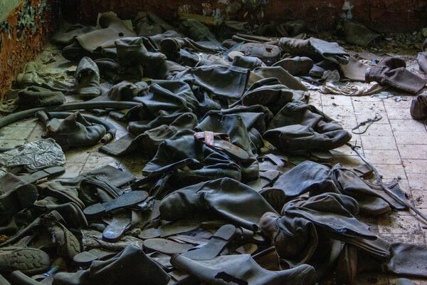 Những đôi bốt cũ chồng la liệt trong cơ sở bí mật Dvina bị bỏ hoang ở thị trấn Postav, Belarus  - Sputnik Việt Nam