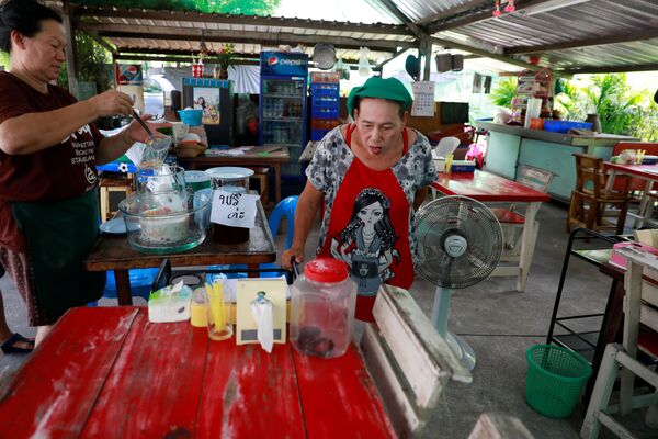 Một người bán hàng rong nhìn vào con rắn hổ mang bị bắt và nhốt trong chai nhựa ở Bangkok, Thái Lan - Sputnik Việt Nam