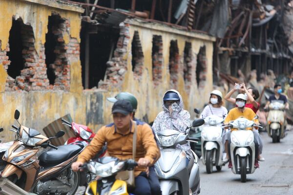 Người dân sinh sống tại đây phải đeo khẩu trang mỗi khi đi qua khu vực cháy nhà máy Bóng đèn Phích nước Rạng Đông. - Sputnik Việt Nam