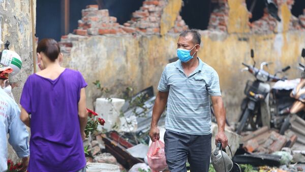 Người dân sinh sống tại đây phải đeo khẩu trang mỗi khi đi qua khu vực cháy nhà máy Bóng đèn Phích nước Rạng Đông.  - Sputnik Việt Nam